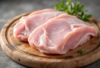 도마 위에 놓인 신선한 칠면조 고기 조각과 허브, 마늘